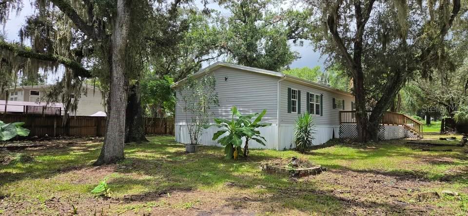 A light gray manufactured home sits on a grassy lot surrounded by large, mossy trees — 5301 ROYAL OAK DRIVE, TAMPA, FL
