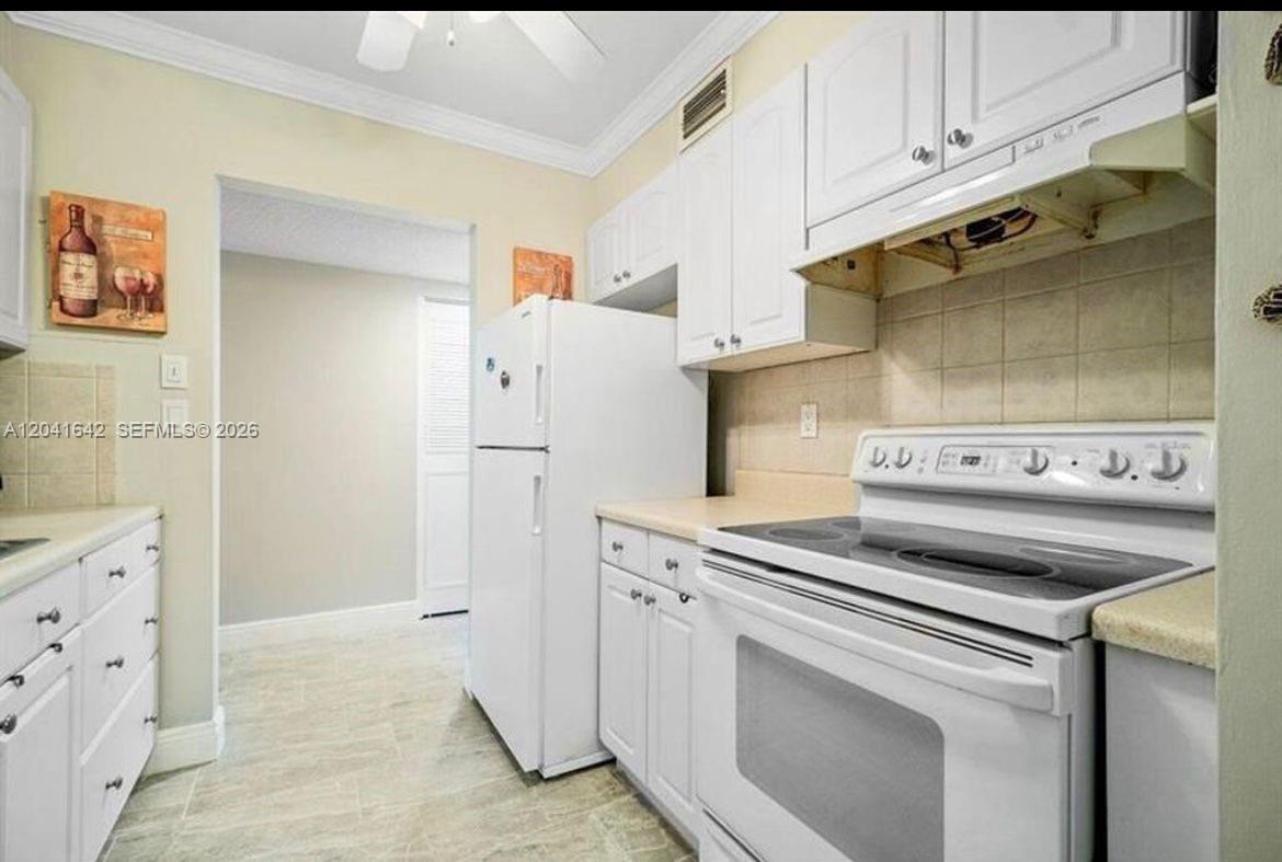 A galley-style kitchen features white cabinetry, a white stove, and a double stainless steel sink — 250 NE 20th St # 3030, Boca Raton FL 33431, BOCA RATON, FL