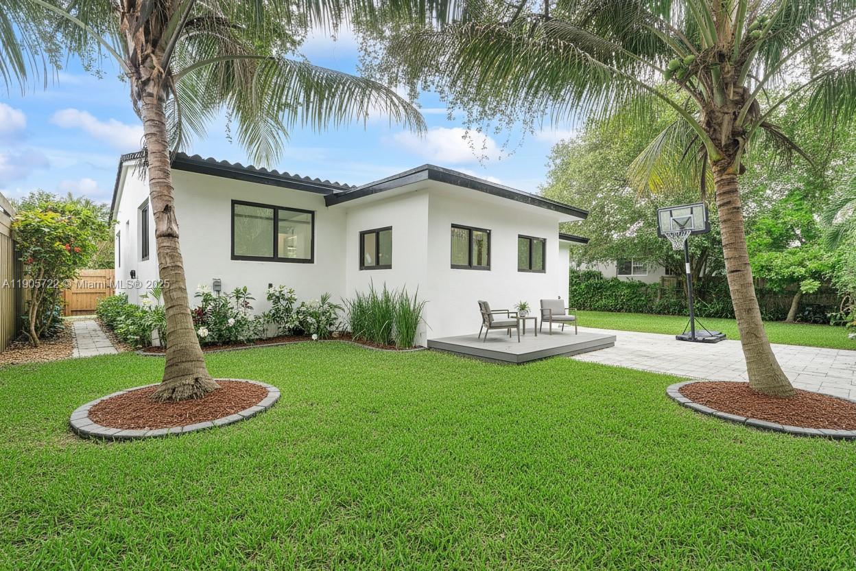 A white house with a gray deck sits in a grassy backyard with palm trees — 8635 N Miami Ave, Miami FL 33150, MIAMI, FL