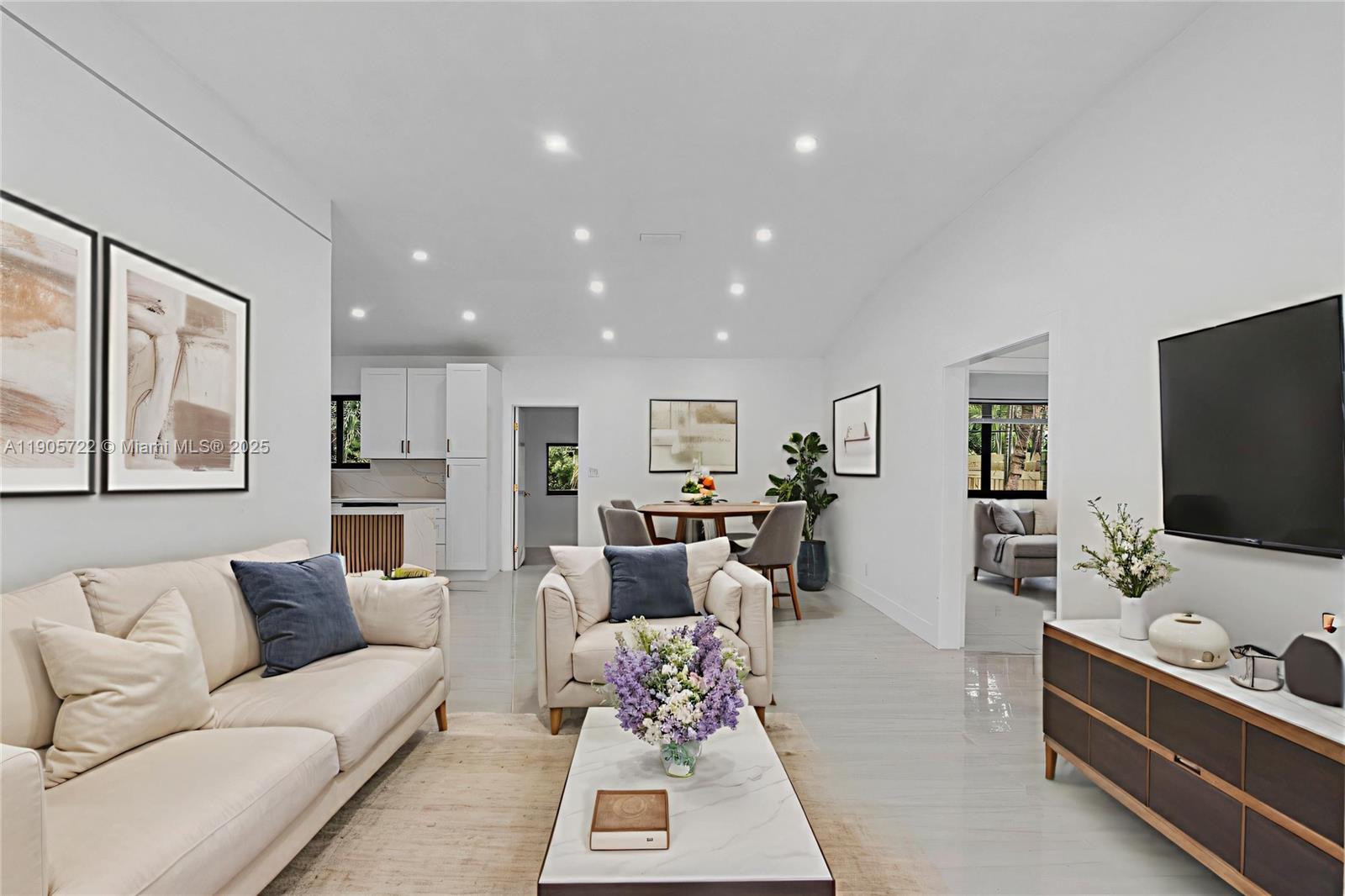 A bright living room features a white sofa, armchair, coffee table, and television console — 8635 N Miami Ave, Miami FL 33150, MIAMI, FL