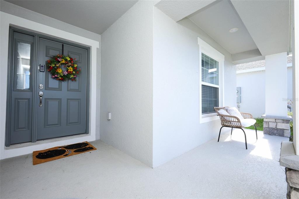 A covered front porch features a gray door with a wreath and a wicker chair — 2459 MATTERHORN TRAIL, DAVENPORT, FL
