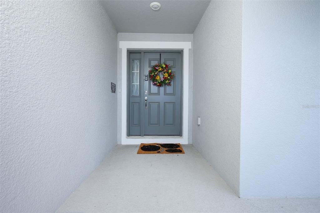 A gray front door with a floral wreath sits under a covered entryway — 2459 MATTERHORN TRAIL, DAVENPORT, FL