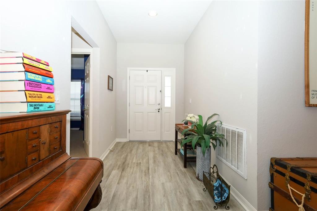 An entryway with light wood-look flooring, a white front door, and a stack of books — 2459 MATTERHORN TRAIL, DAVENPORT, FL