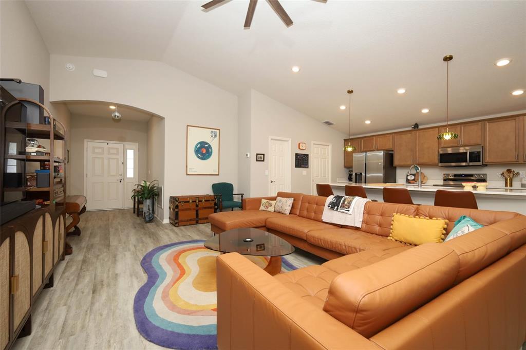 A living room with a large tan sectional, a rainbow rug, and an open kitchen — 2459 MATTERHORN TRAIL, DAVENPORT, FL
