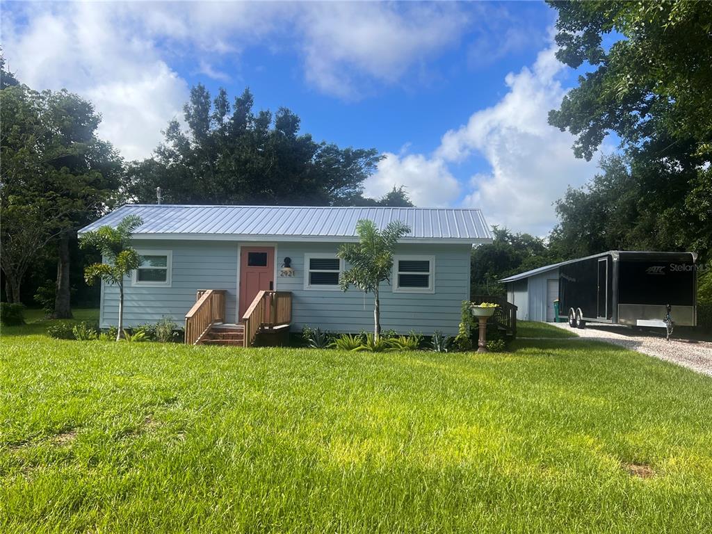A light blue single-story house with a metal roof and a detached trailer parked nearby — 2921 WILSON AVENUE, PUNTA GORDA, FL