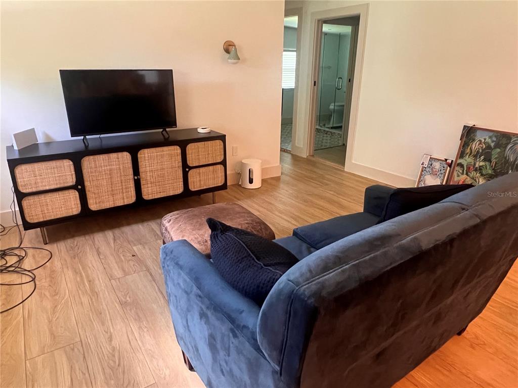 A living room features a dark blue sofa, a rattan media console, and wood-look flooring — 2921 WILSON AVENUE, PUNTA GORDA, FL
