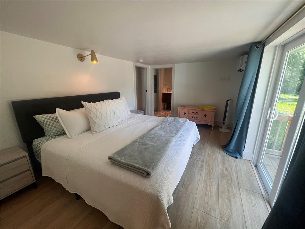 A bedroom features a bed with white bedding, wood-look flooring, and a sliding glass door — 2921 WILSON AVENUE, PUNTA GORDA, FL