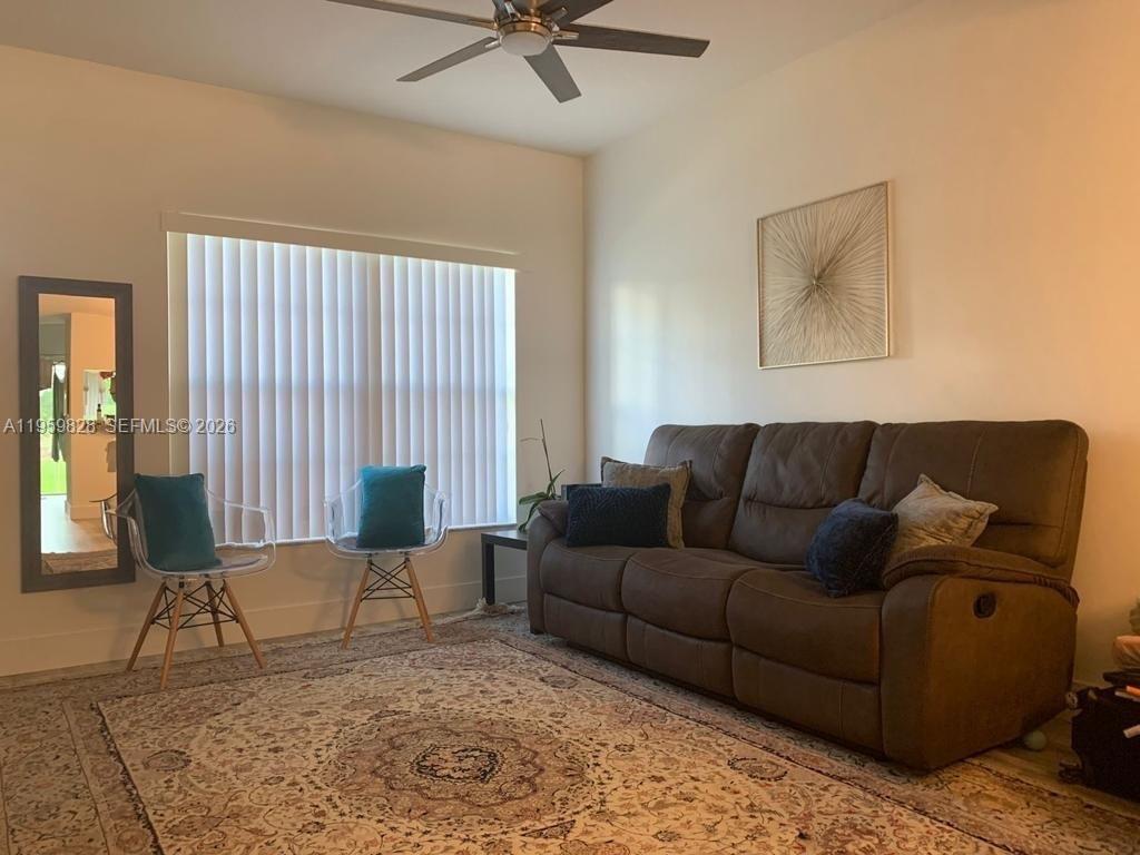 A living room features a brown sofa, two clear chairs, and a large area rug — 20 Key West Ct, Weston FL 33326, WESTON, FL