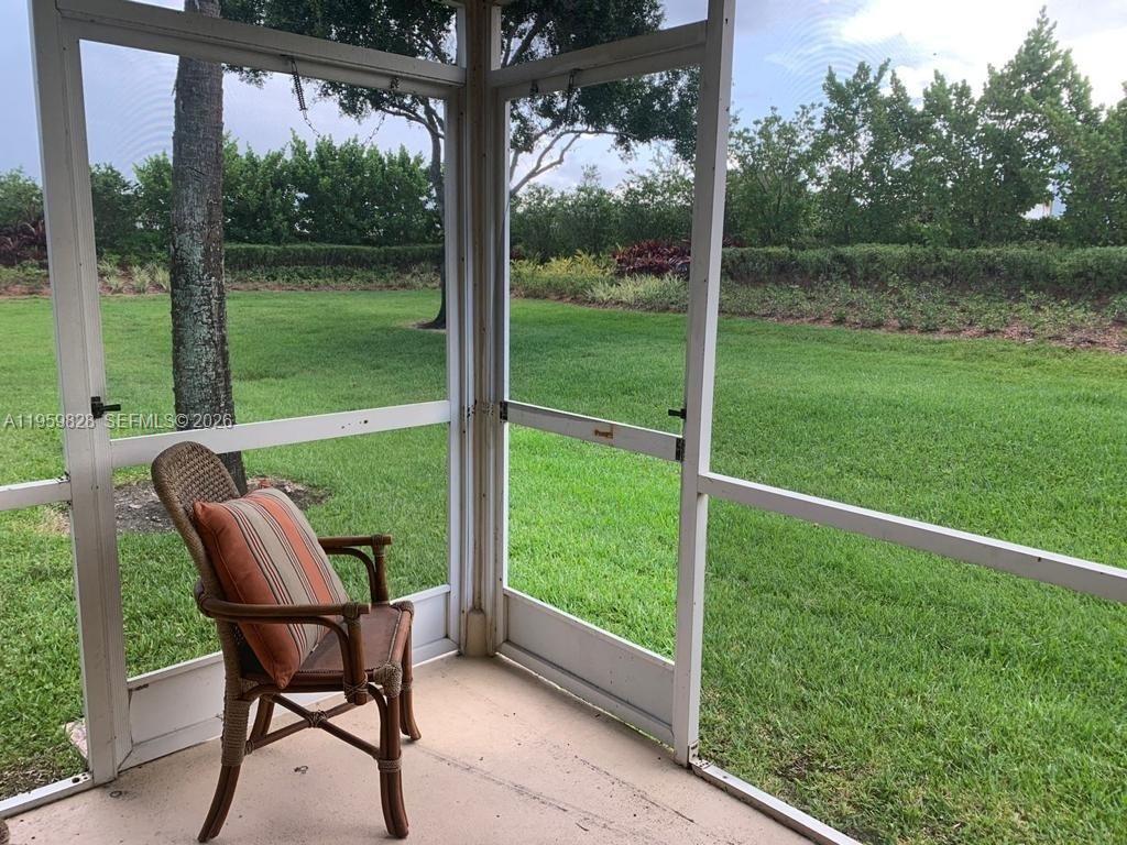 A screened-in porch features a wicker chair and a view of a grassy backyard — 20 Key West Ct, Weston FL 33326, WESTON, FL
