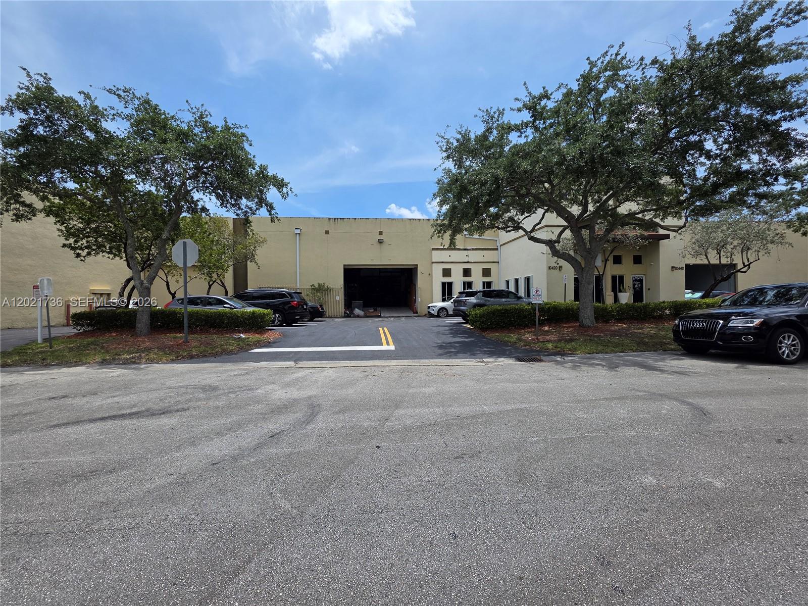An exterior view of a commercial warehouse building with a loading bay and parking lot — 10420 NW 37th Ter, Doral FL 33178, DORAL, FL