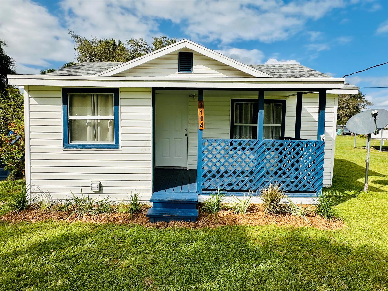 A small white cottage with blue trim, a front porch, and a lattice railing — 1104 SW 11th Street, Okeechobee FL 34974, OKEECHOBEE, FL