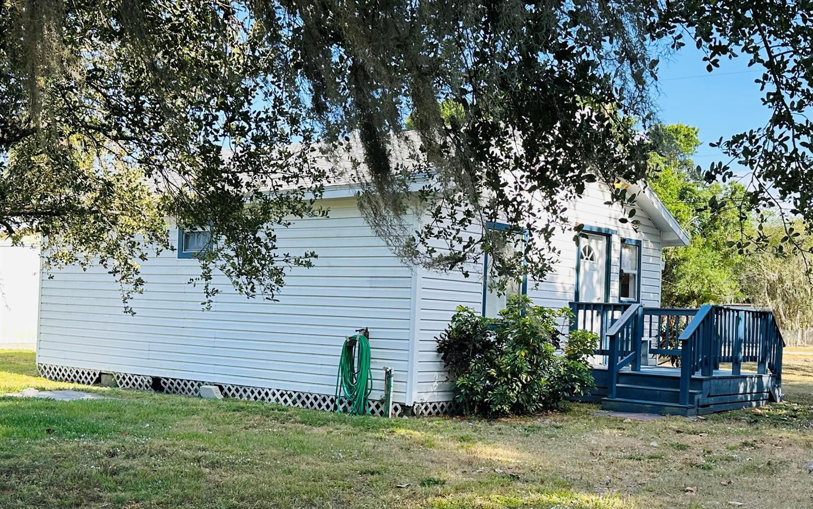 A white house with blue trim and a wooden deck sits on a grassy lot — 1104 SW 11th Street, Okeechobee FL 34974, OKEECHOBEE, FL