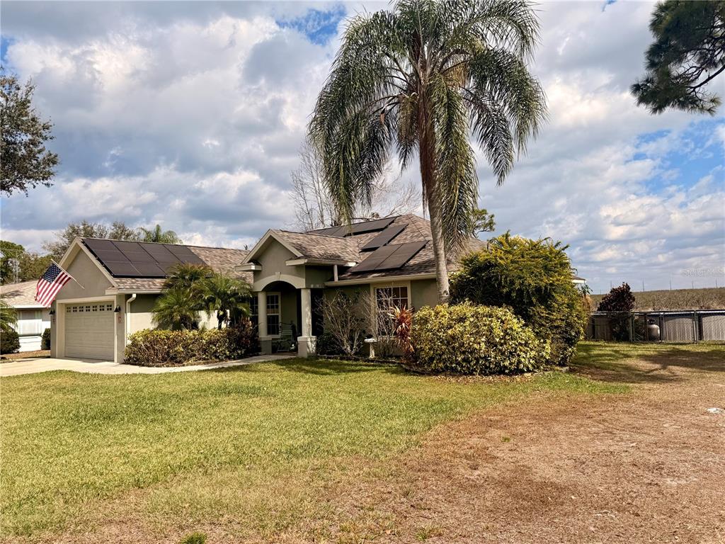A single-story house with a garage, solar panels on the roof, and a palm tree — 478 HUMPHREY AVENUE, LAKE PLACID, FL