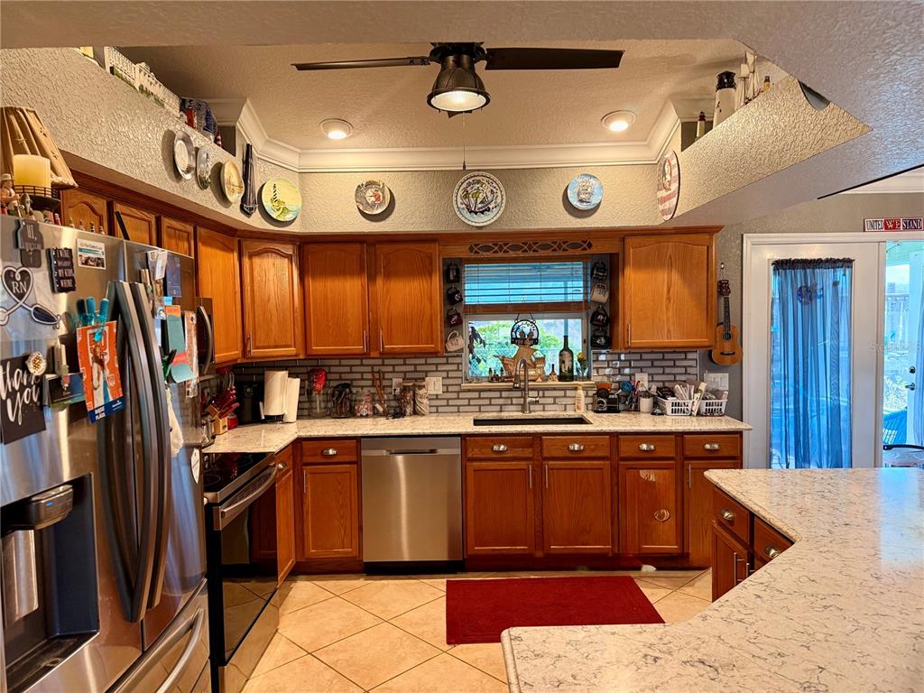 A kitchen features wood cabinets, stainless steel appliances, a tiled backsplash, and a center island — 478 HUMPHREY AVENUE, LAKE PLACID, FL