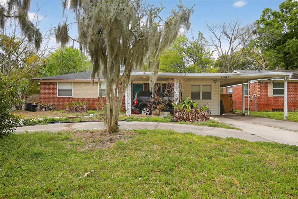 A single-story brick house features a large tree in the front yard and a carport — 1324 PLACID PLACE, JACKSONVILLE, FL
