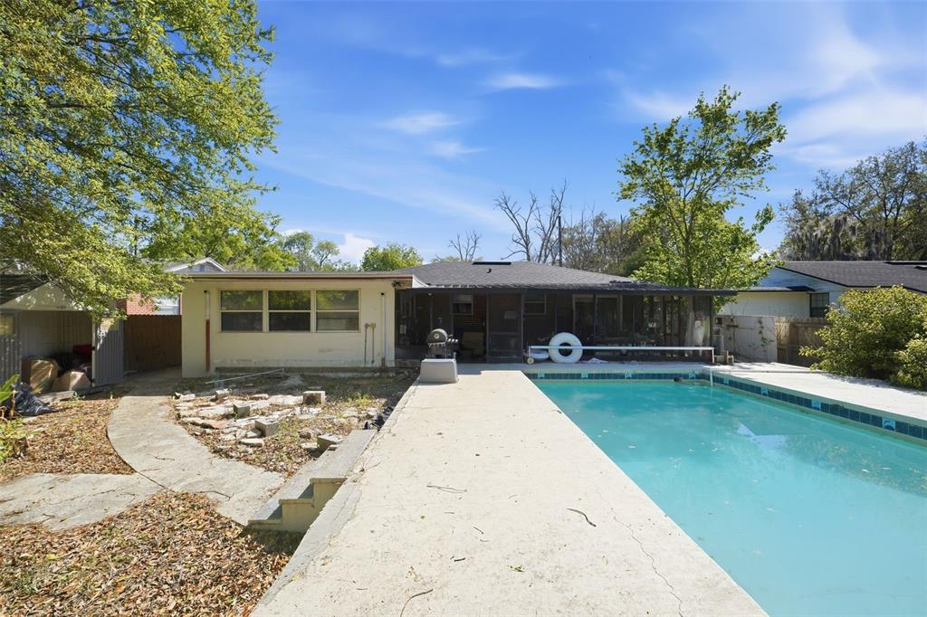A backyard features a rectangular swimming pool, a concrete patio, and a single-story house exterior — 1324 PLACID PLACE, JACKSONVILLE, FL