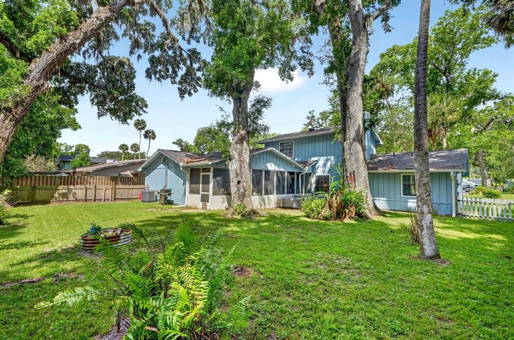 A blue two-story house with a screened-in porch sits in a large, tree-filled backyard — 855 SUGAR HOUSE DRIVE, PORT ORANGE, FL