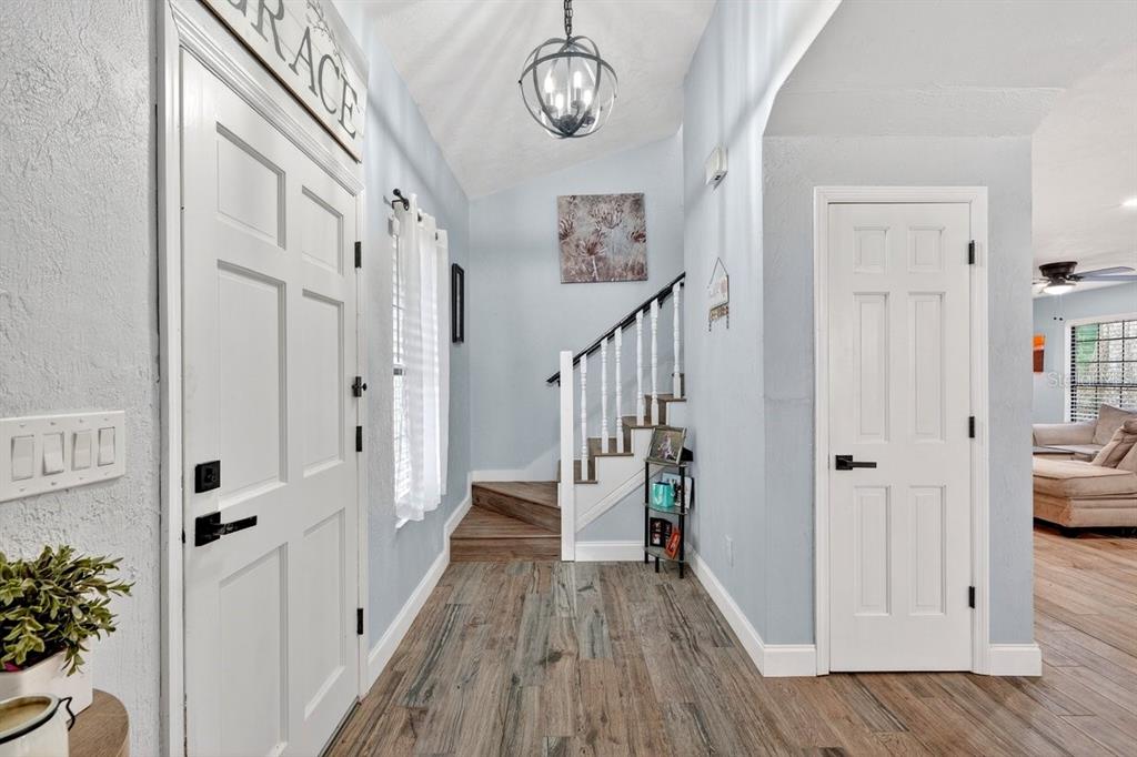 An entryway features wood-look tile flooring, a white staircase, and a light blue wall color — 855 SUGAR HOUSE DRIVE, PORT ORANGE, FL