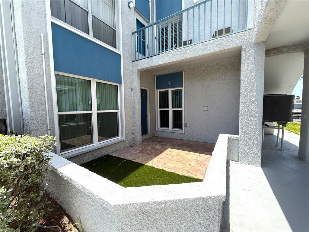 A ground-level patio features a small patch of artificial turf and a stone-tiled floor — 201 MEDALLION BOULEVARD UNIT D, MADEIRA BEACH, FL