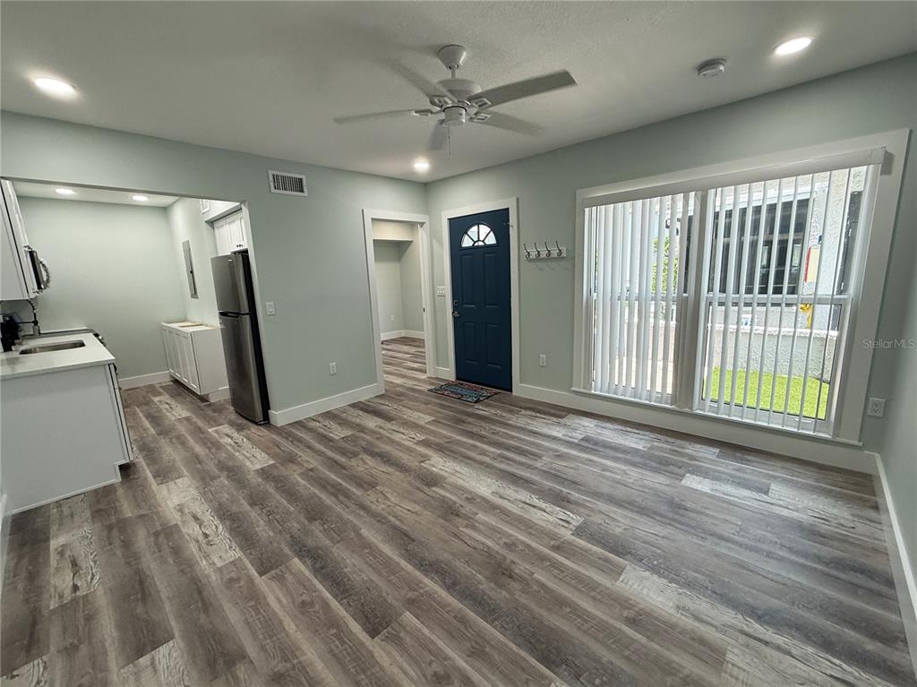 A room with light-colored walls, wood-look flooring, a ceiling fan, and a blue front door — 201 MEDALLION BOULEVARD UNIT D, MADEIRA BEACH, FL