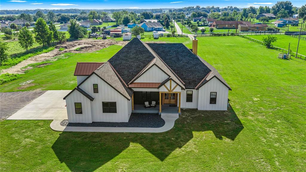 An aerial view of a modern farmhouse with white siding, dark roofing, and a front porch — 9755 SE 58TH AVENUE, BELLEVIEW, FL