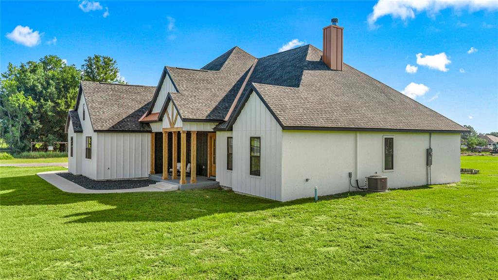 A white farmhouse with a dark shingled roof and wooden porch columns sits on grass — 9755 SE 58TH AVENUE, BELLEVIEW, FL