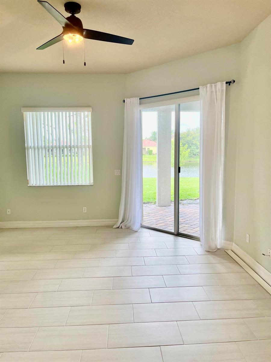 A room with light-colored tile flooring, a ceiling fan, a window, and sliding glass doors — 5579 55th Avenue, Vero Beach FL 32967, VERO BEACH, FL