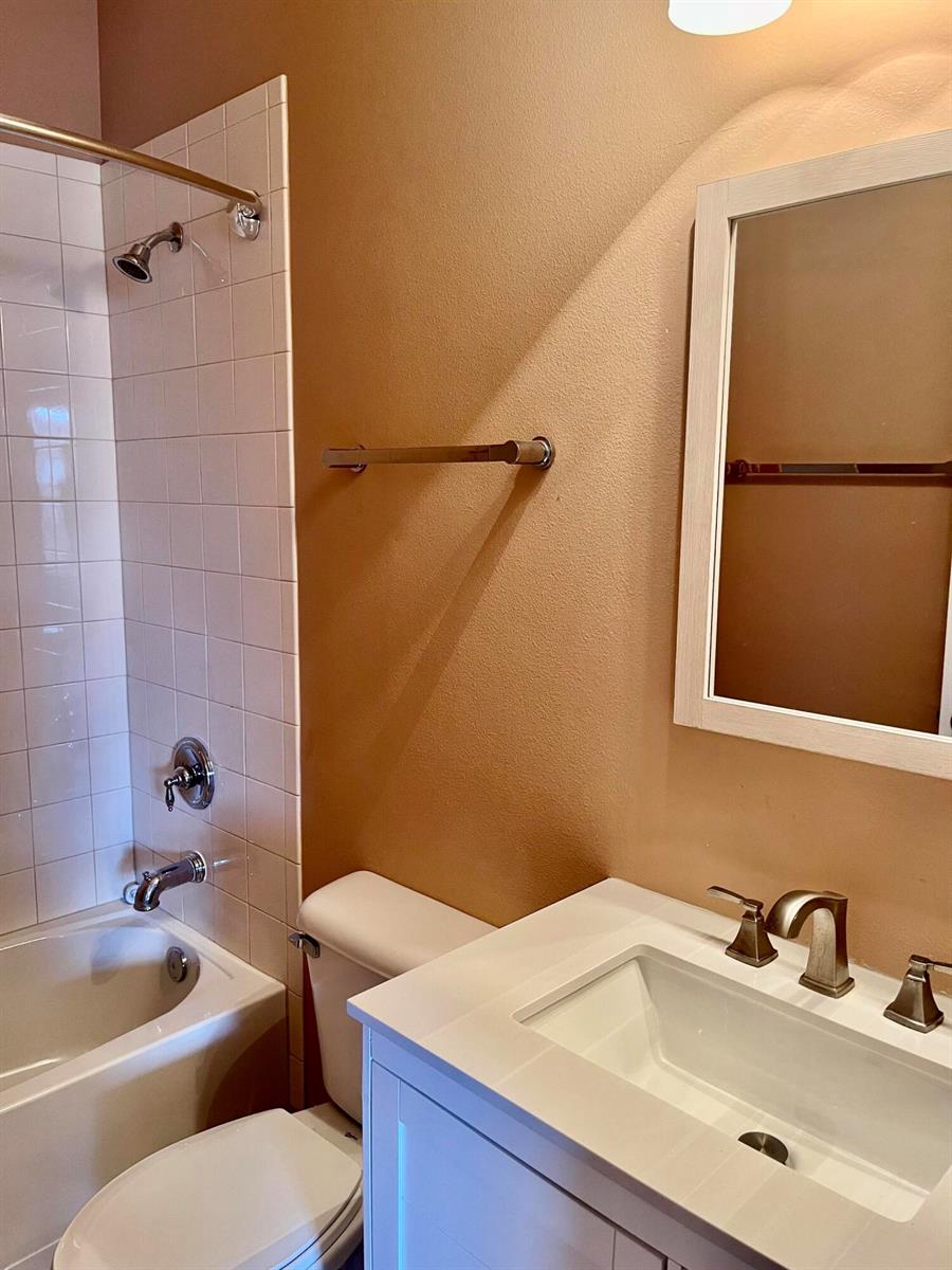 A bathroom features a white vanity, a toilet, and a shower-tub combination with white tiles — 5579 55th Avenue, Vero Beach FL 32967, VERO BEACH, FL