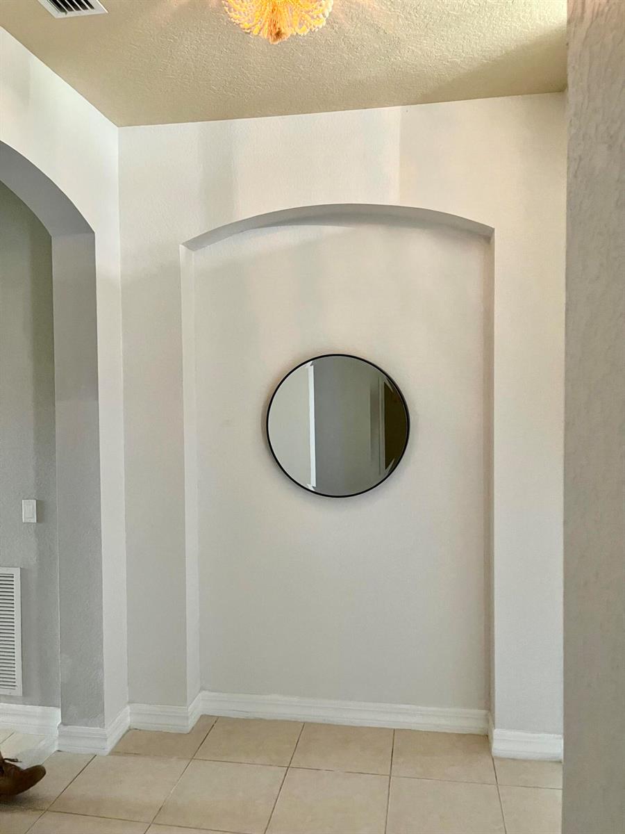 A circular mirror hangs on the back wall of an arched alcove in a hallway — 5579 55th Avenue, Vero Beach FL 32967, VERO BEACH, FL