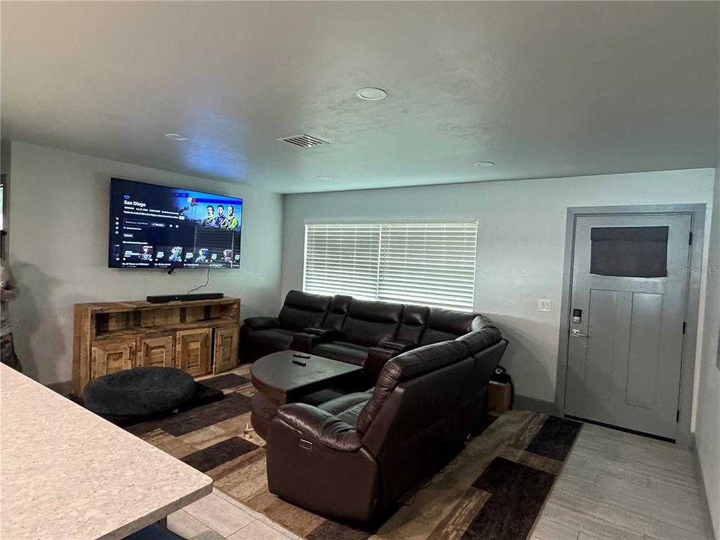 A living room features a large sectional sofa, a wooden media console, and a wall-mounted television — 2436 CLAIRE AVENUE, NEW SMYRNA BEACH, FL