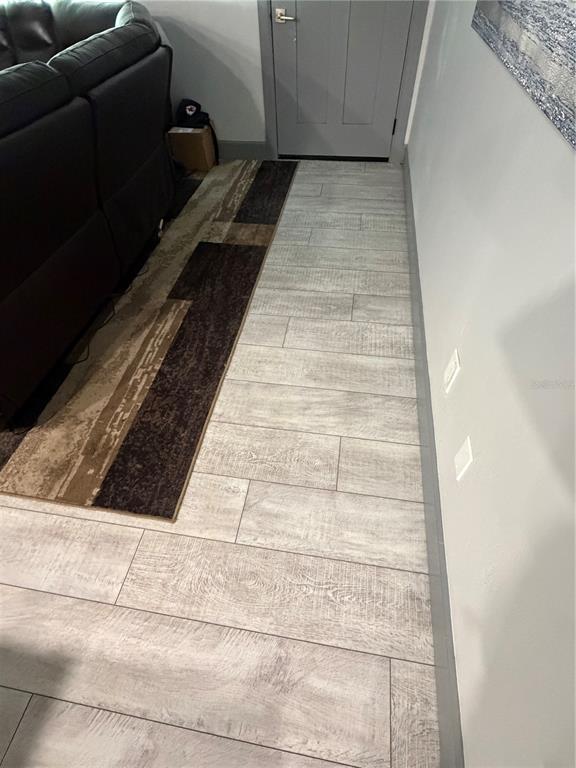 A hallway with light wood-look tile flooring and a dark area rug beside a sofa — 2436 CLAIRE AVENUE, NEW SMYRNA BEACH, FL