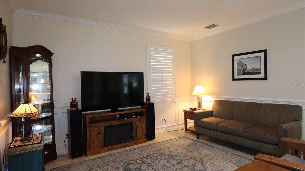A living room features a television on a wooden stand, a sofa, and a curio cabinet — 2293 NW 58TH TERRACE, OCALA, FL
