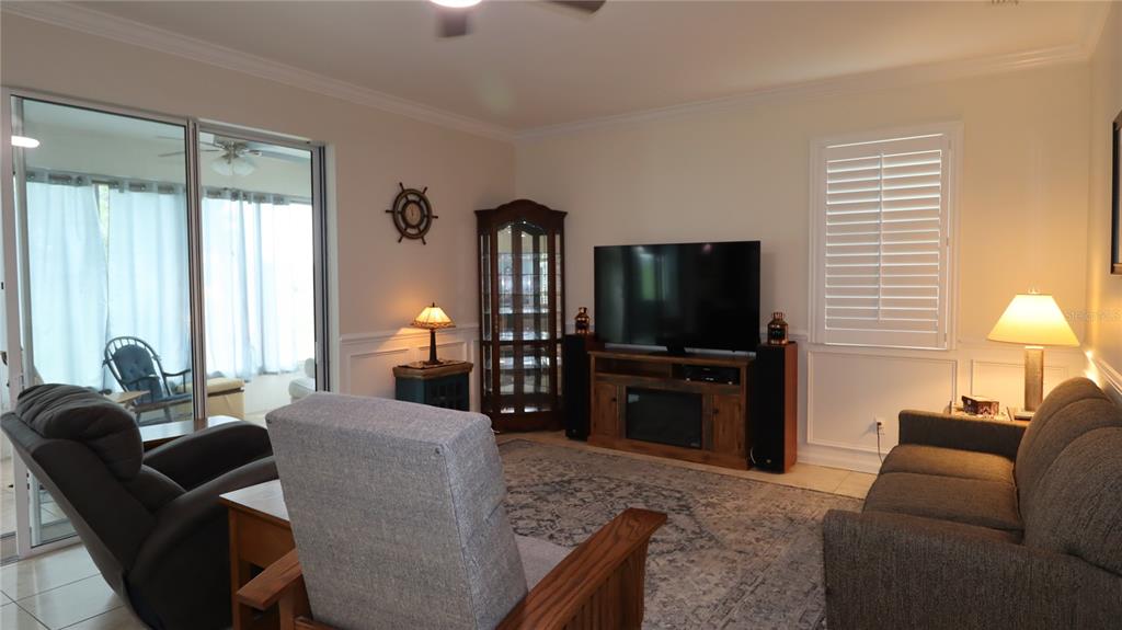 A living room features a television on a wooden stand, two sofas, and sliding glass doors — 2293 NW 58TH TERRACE, OCALA, FL