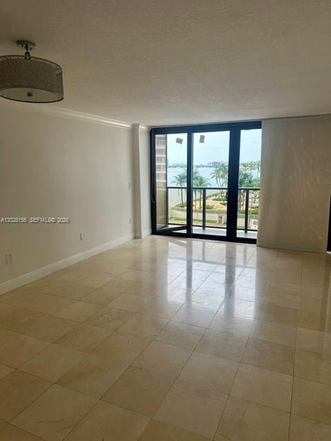 An empty room with light-colored tile flooring, a drum pendant light, and a balcony view — 600 NE 36th St # 516, Miami FL 33137, MIAMI, FL