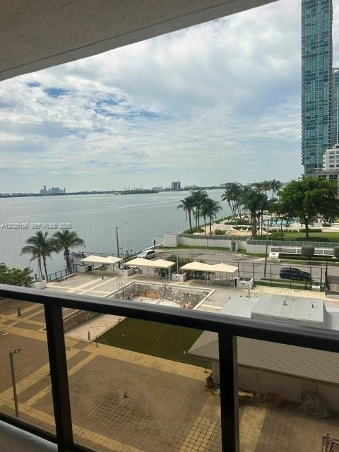 A balcony view overlooks a swimming pool, palm trees, a parking lot, and the bay — 600 NE 36th St # 516, Miami FL 33137, MIAMI, FL