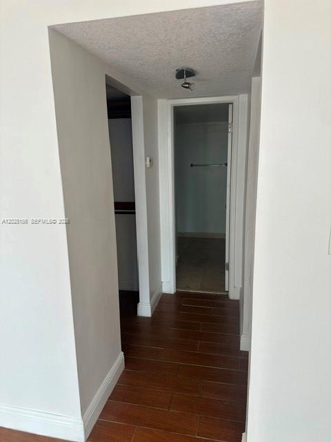 A hallway with wood-look tile flooring leads to an open doorway showing a bathroom — 600 NE 36th St # 516, Miami FL 33137, MIAMI, FL