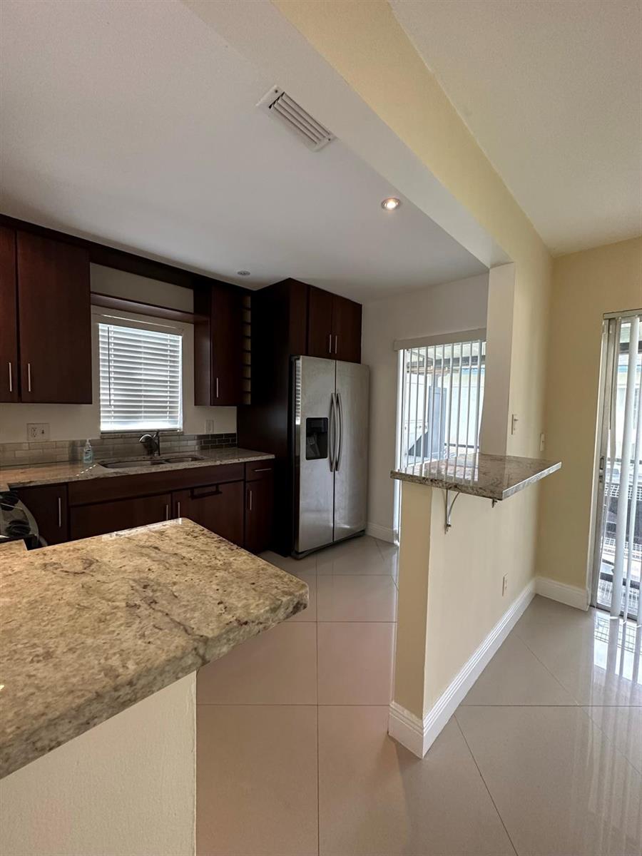 A kitchen features dark wood cabinets, granite countertops, stainless steel appliances, and light tile flooring — 3001 NW 4th Terrace # 152, Pompano Beach FL 33064, POMPANO BEACH, FL