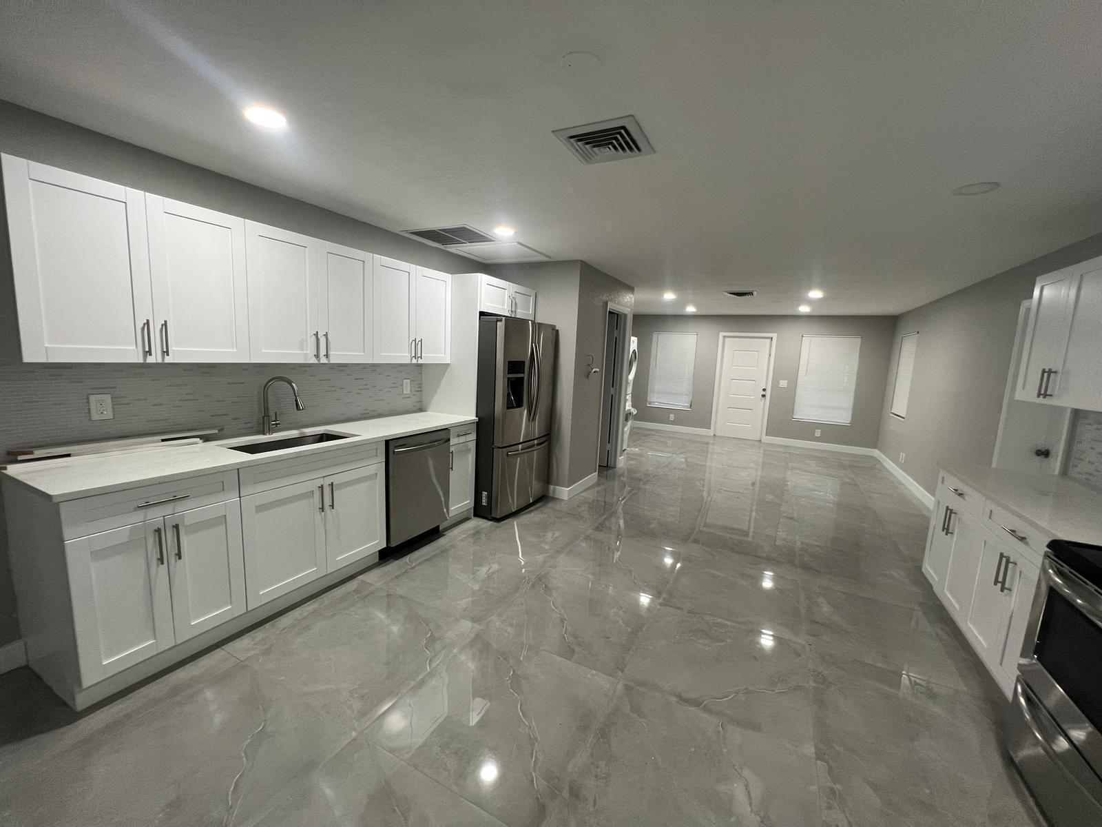 A kitchen with white cabinets, stainless steel appliances, and gray marble-look tile flooring — 129 Euclid Boulevard, Lantana FL 33462, LANTANA, FL