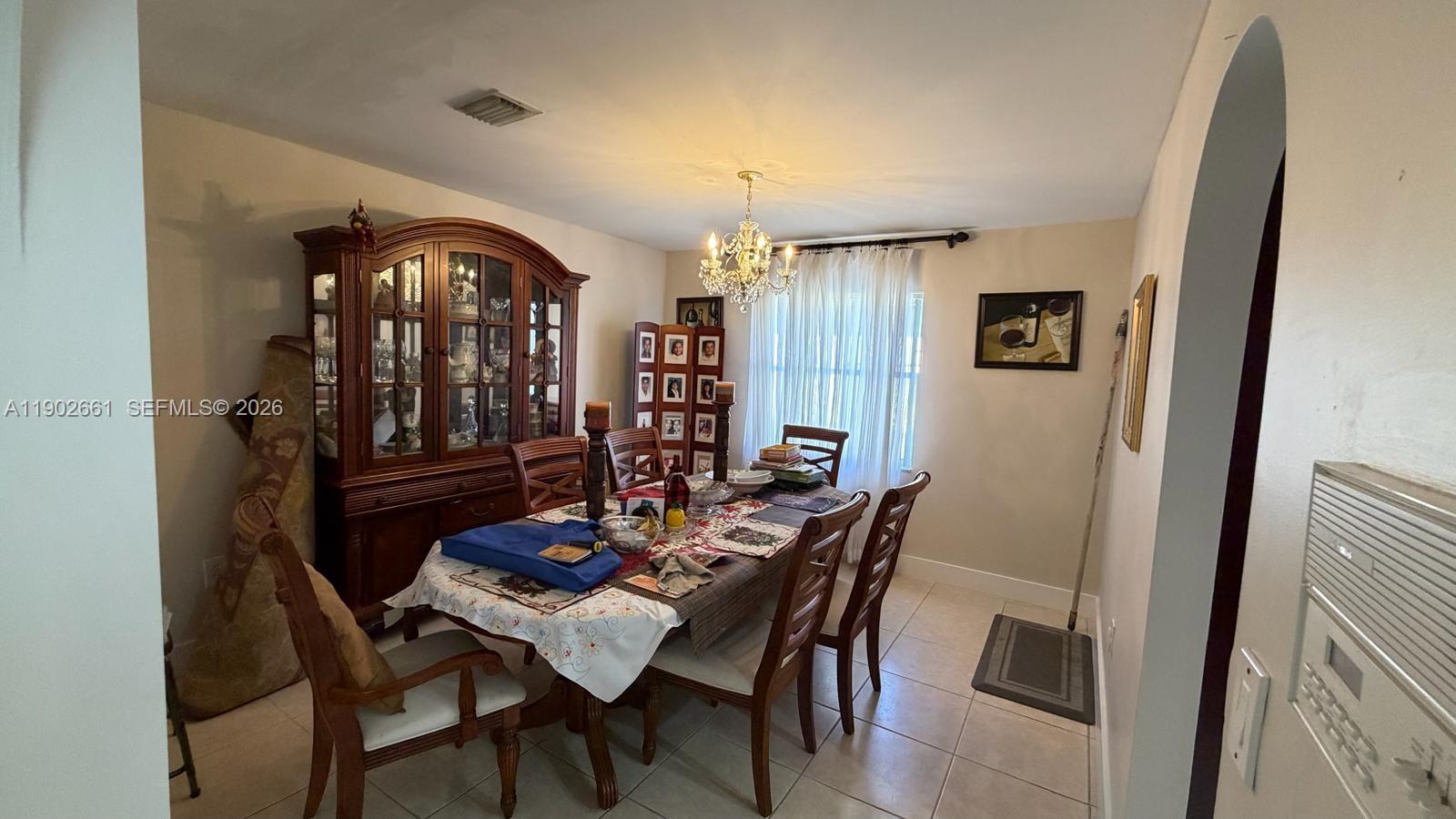 A dining room features a wooden hutch, a chandelier, and a table with chairs — 14713 SW 155th Pl, Miami FL 33196, MIAMI, FL