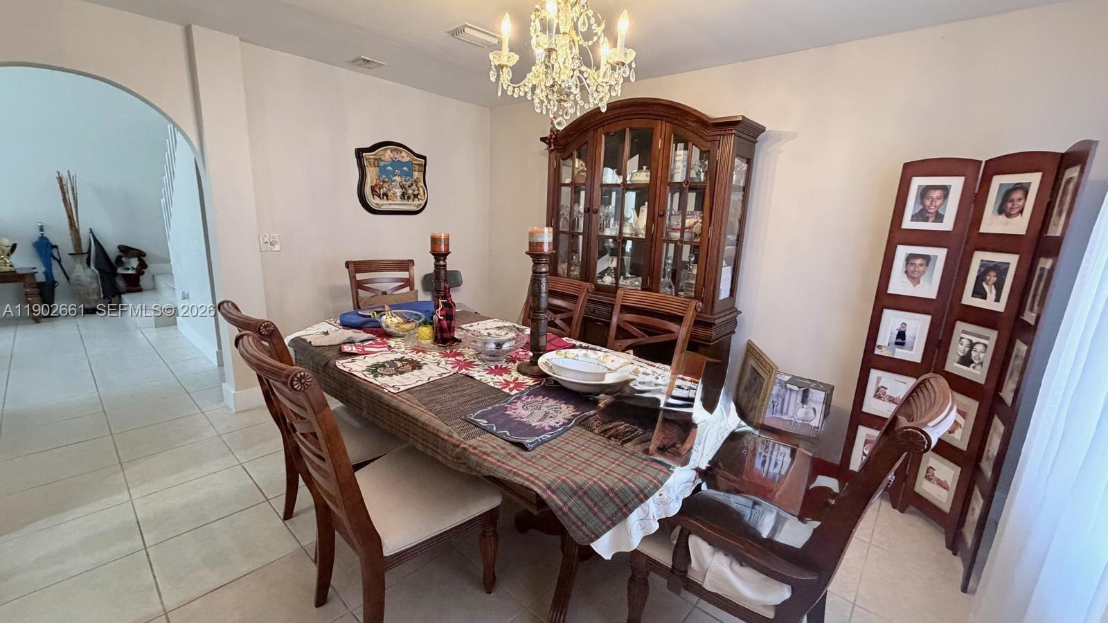 A dining room features a wooden table, a matching hutch, and a photo display screen — 14713 SW 155th Pl, Miami FL 33196, MIAMI, FL