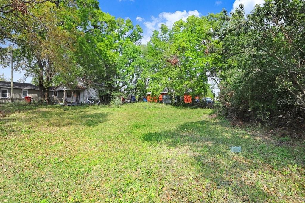 A grassy lot with trees and two small houses in the background — 710 E OHIO STREET, PLANT CITY, FL
