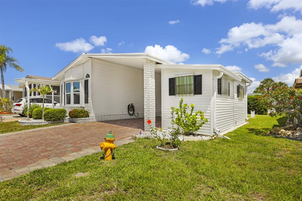 A white mobile home with a brick driveway, a carport, and a yellow fire hydrant — 2100 KINGS HIGHWAY UNIT 744, PORT CHARLOTTE, FL