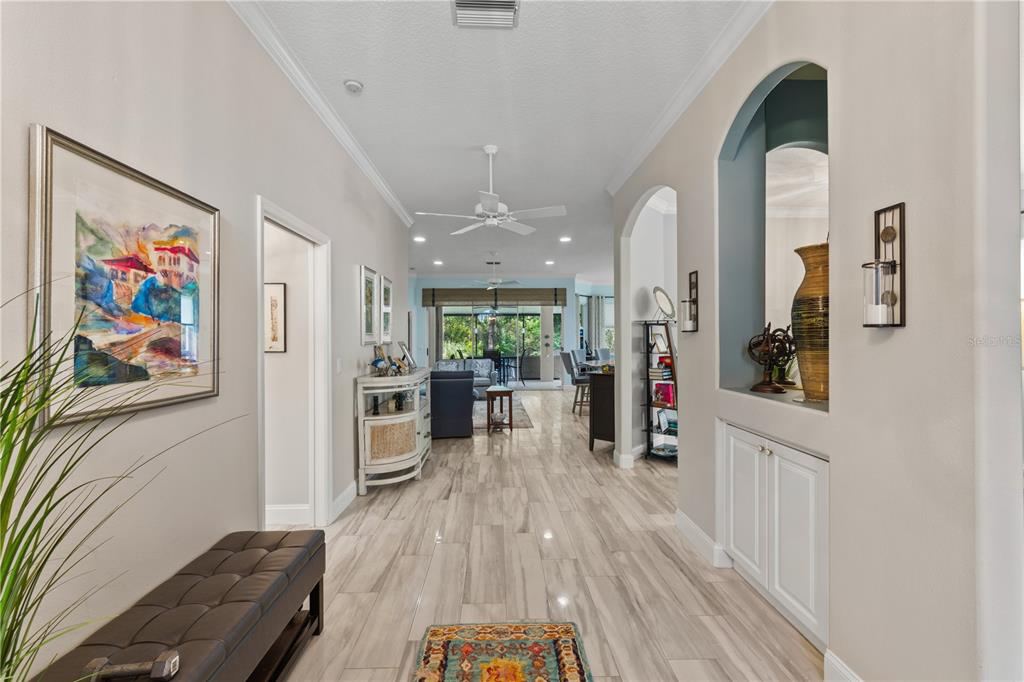 A bright hallway with light wood-look tile floors leads toward an open living area — 5948 SANDSTONE AVENUE, SARASOTA, FL