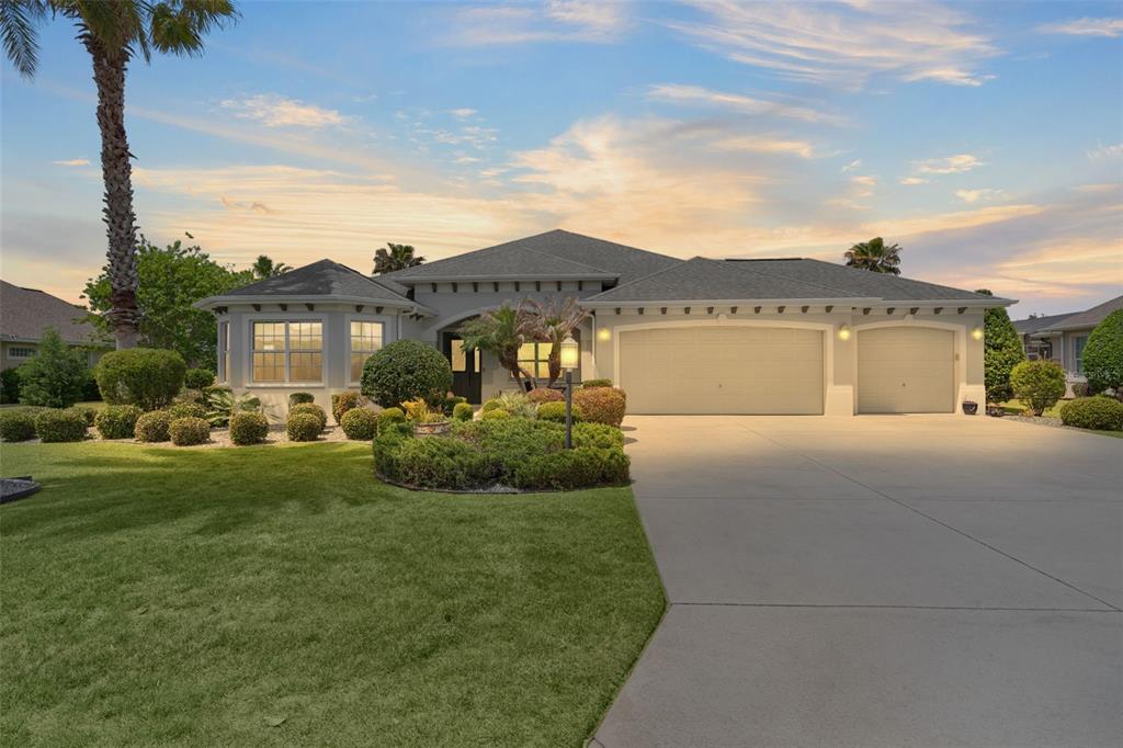 A single-story house with a three-car garage, a landscaped front yard, and a palm tree — 2254 ISLEWORTH CIRCLE, THE VILLAGES, FL