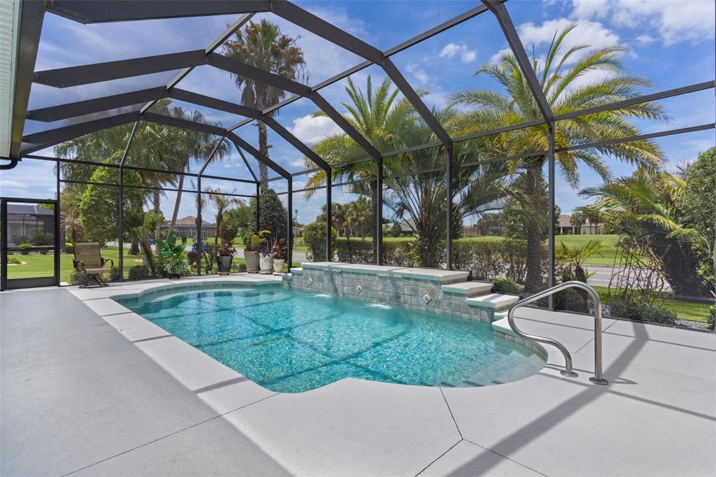 A screened-in swimming pool with a water feature and palm trees in the background — 2254 ISLEWORTH CIRCLE, THE VILLAGES, FL