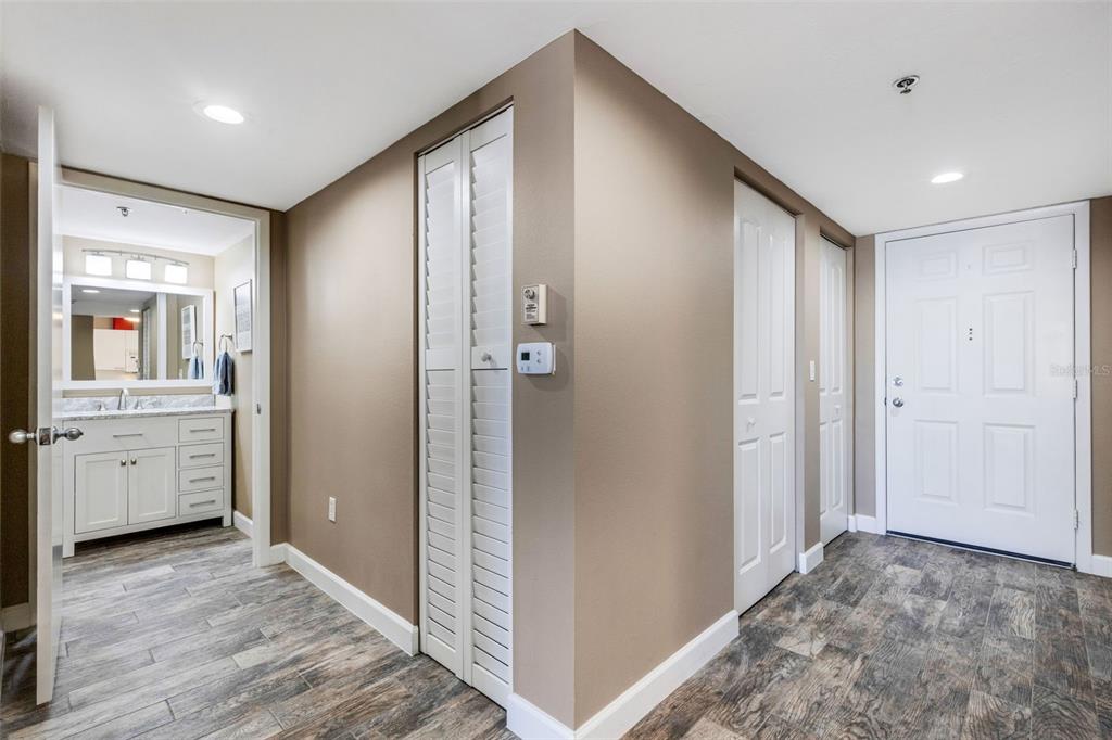 A hallway with wood-look tile flooring leads to a bathroom and an entry door — 3980 IRONWOOD CIRCLE UNIT 404, BRADENTON, FL