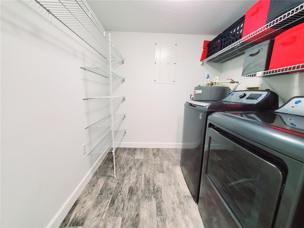 A laundry room features a wire shelving unit, a water heater, and a washer-dryer set — 3980 IRONWOOD CIRCLE UNIT 404, BRADENTON, FL