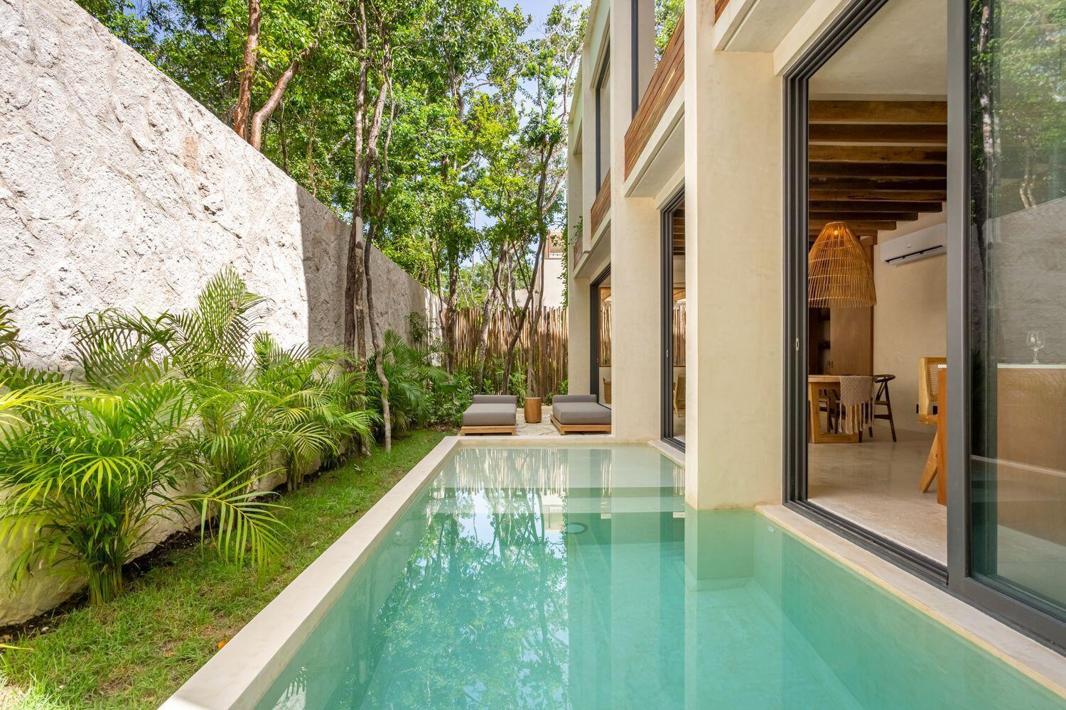 A modern house features a narrow swimming pool, a stone wall, and a patio area — Amari Tulum 10 Avenida Norte & Calle Palma, FL
