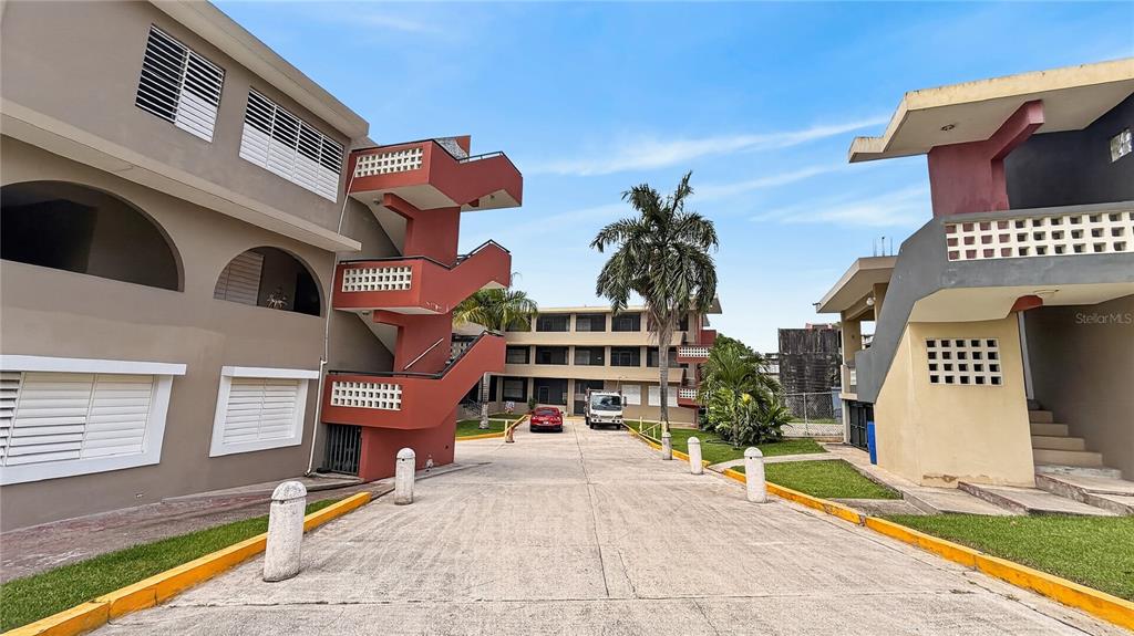 An exterior view of apartment buildings with a central driveway and a red staircase — 120 BO HATO TEJAS, CALLE PAJAROS, BAYAMON, PR