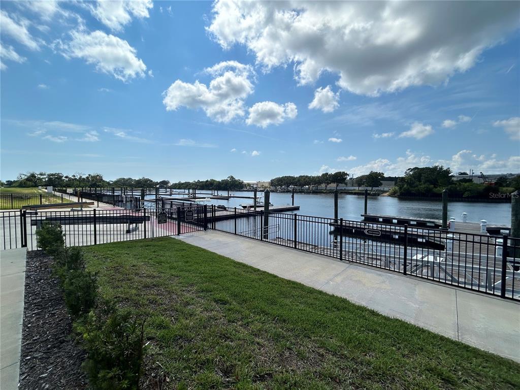 A paved walkway leads to a fenced boat dock overlooking a canal under a cloudy sky — 24 DEL PALMA DRIVE, PALM COAST, FL